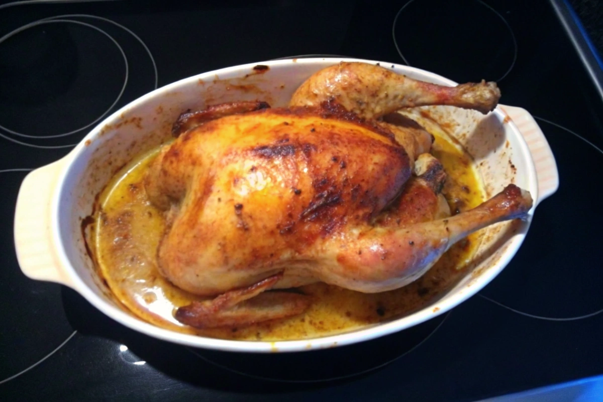 Poulet rôti à l'orientale coloré posé sur un plat en terre cuite